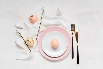 Beautiful table setting with Easter eggs and willow branches on white background
