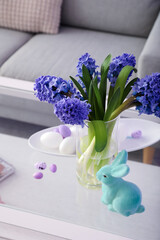 Vase with hyacinth flowers, Easter bunny and eggs on table