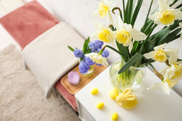 Beautiful flowers, Easter eggs and bunny near light wall