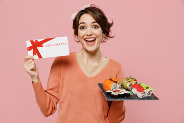 Young happy woman 20s in casual clothes hold in hand makizushi sushi roll served on black plate...