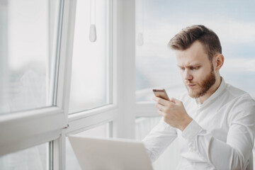 Fototapeta premium male manager in the office texting on a smartphone while working