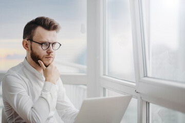 man sits at the workplace in the office by the window and ponders the difficult task of economic sanctions.