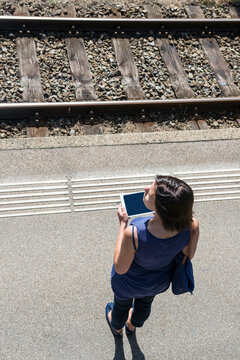 Aerial View of a Woman Waiting on Railroad Station and Using Smartphone with Tracks in Bellinzona, Switzerland.