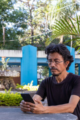 guatemalan man using cellphone while sitting outdoors