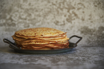 Delicious pancakes on a vintage metal platter on a concrete surface.
