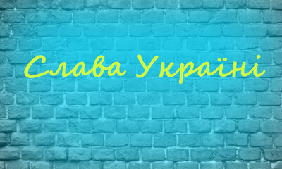Brick blue wall with yellow inscription GLORY to Ukraine on Ukrainian language