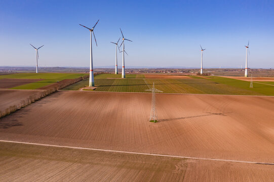 Luftbild von einem ländlichen Gebiet mit einem riesigen Windpark und Strommasten für die teure Energiewende in Deutschland