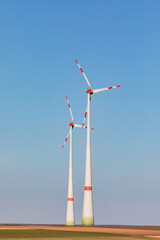 Two wind turbines dominate nature, upright image