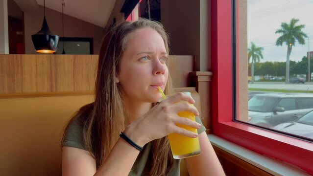 Young woman sits in a restaurant and drinks orange juice - travel photography