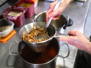 Cook squeezing juice out of food using a strainer in a restaurant kitchen