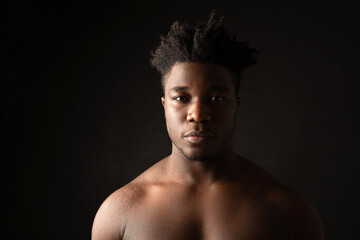 Fototapeta premium portrait of an african male with muscles on a black background 