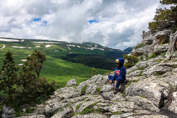 A little boy on the background of the alpine meadows of the Lago-Naki plateau in Adygea. Russia. 2021.
