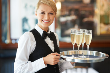 Sparkle with a refreshing glass of classy champagne. Friendly waitress holding up a tray of champagne glasses in her hands at a celebration party.