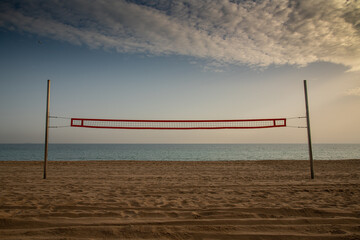 A beach volleyball court on a wild beach with a calm sea in the background awaits travelers...