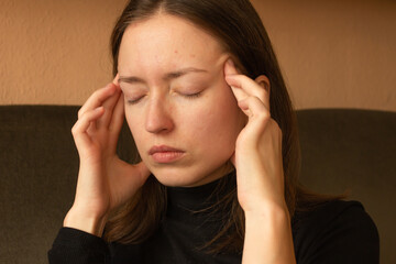Portrait of stressed young brunette woman massaging temples, feeling strong headache pain or migraine.