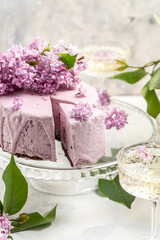 Obraz na płótnie Canvas a piece of mousse cake, Delicious dessert blueberry tart with fresh berries with a bouquet of purple blooming lilacs, vertical image place for text