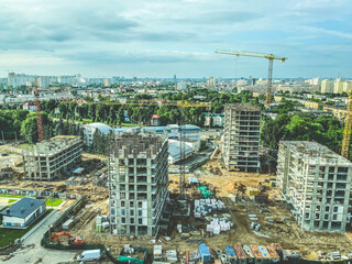 Obraz premium construction of a new residential complex in the city center. view of the construction site from above. construction of high-rise buildings from blocks using a metal crane