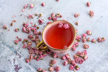 Rose buds tea in a pink cup .
Tea made from tea rose petals