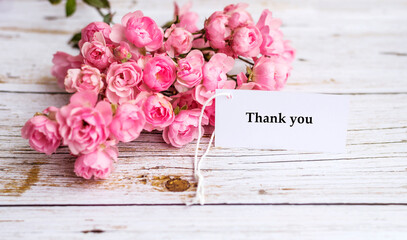 Thank you greeting card with beautiful pink roses on a white wooden background 