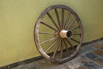 Obsolete vintage wooden wheel on faded yellow wall background