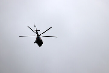 Silhouette of russian helicopter in flight on gray sky background