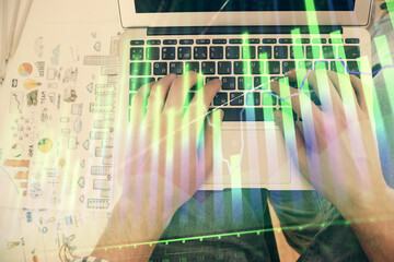 Double exposure of man's hands typing over laptop keyboard and forex chart hologram drawing. Top view. Financial markets concept.