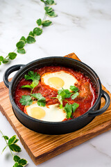 Shakshuka in a Cast Iron Pan. Middle eastern style eggs in tomato and pepper sauce with parsley for breakfast.