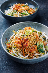 Modern style traditional stir-fried Thai phak kung with king prawns, vegetable and noodles served as close-up in a Nordic design bowl