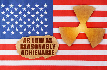 On the US flag, the symbol of radioactivity and torn cardboard with the inscription - As Low As Reasonably Achievable