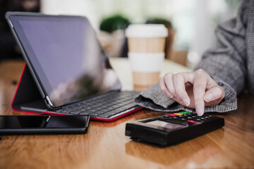 business woman in cafe doing contact less payment, introducing secret number. digital tablet besides