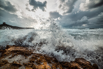 Wave crashing against the rocks in San Giovanni di Sinis at sunset