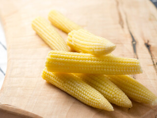 Pickled young corn cobs on a wooden board, milk corn cobs. copy space