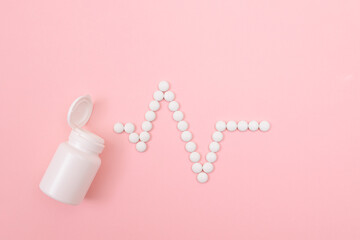 Heartbeat Rhythm. Electrocardiogram. ECG Line Made from White Pills Scattered from the Pill Container, Lying on Pink Background. Global Pharmaceutical Industry and Medicinal Products