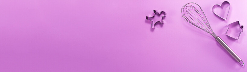 Banner of steel whisk house men and heart shaped cutter flat lay top view. Confectionery cooking concept with copy space on bright purple paper background