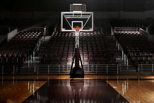 Empty basketball arena with dramatic lighting, view from free throw line in front of goal on the court
