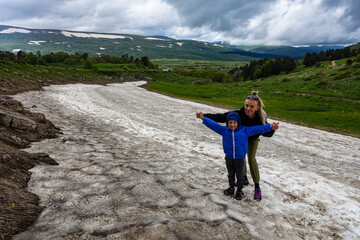 A girl with a child on a glacier on the snowy plateau of Lagonaki in Adygea. Russia. 2021.