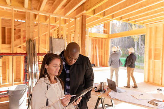 Homeowner couple with digital tablet in house under construction