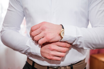 Obraz premium A man fastens a cufflink on his shirt. Groom fastening cufflinks on his shirt
