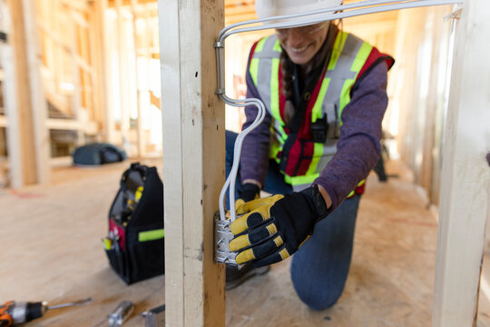 Female electrician installing electrical outlets at construction site