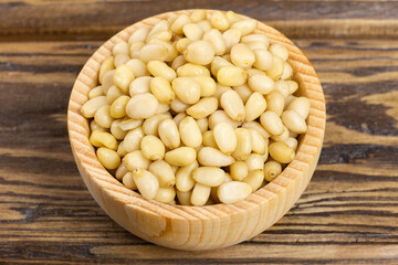 A bowl with pine nuts on a wooden background, delicious, natural. Soft focus.
