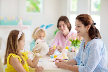 Mother and kids, family coloring Easter eggs.