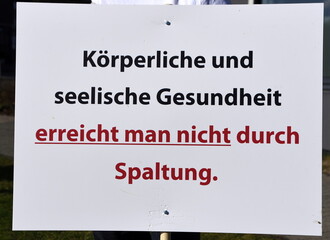 Schild auf einer Corona-Demo: "Körperliche und seelische Gesundheit erreicht man nicht durch Spaltung."