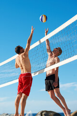 In the heat of the game. Shot of a beach volleyball game on a sunny day.