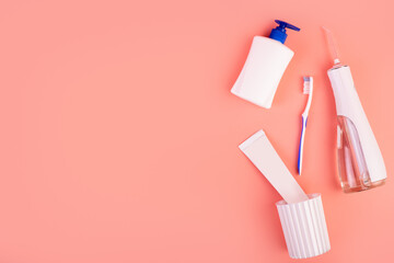 Flat lay composition with manual toothbrush, irrigatoro, toothpaste and oral hygiene products on pink background. Flat lay concept. oral care concept