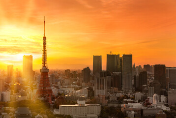 Fototapeta na wymiar tokyo, japan - february 22 2022: Bird's-eye view depicting a gorgeous orange sunset sky above a commercial cityscape of Tokyo tower with no logo and no brand on the surrounding skyscrapers.