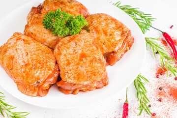 Convenience food, quick cook, semi-cooked food.Chicken thighs marinated in red sauce on a white plate,on white background,banner.