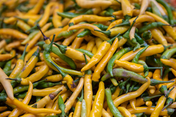 Big pile of yellow chili peppers, also known as pepperoni at street market, freshly harvested. Natural background.