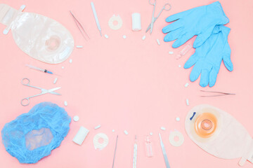 Surgeon's set: from a colostomy bag, surgical instruments, pills, gloves a on a soft pink...