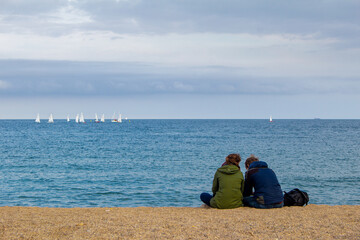 couple on the beach
couple alone on the beack looking at group windsurfing in the background