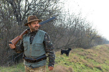Hunter man in camouflage with a gun during the hunt in search of wild birds or game. Autumn hunting...